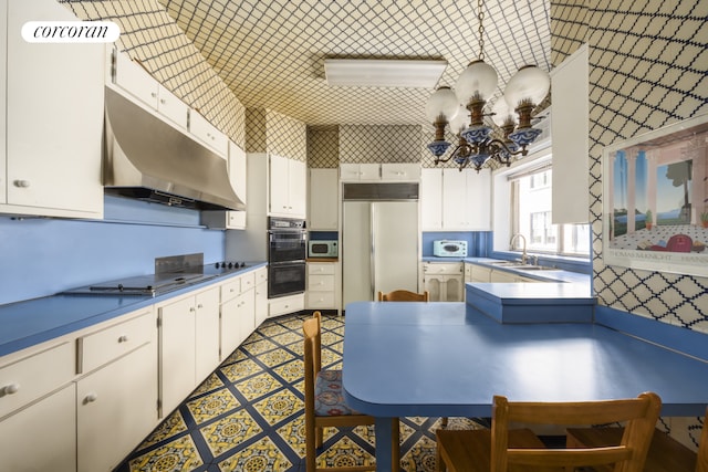 32 E 64th St Unit 5E, New York City, NY 10021 - kitchen featuring paneled fridge, electric stovetop, a chandelier, under cabinet range hood, and white cabinetry
