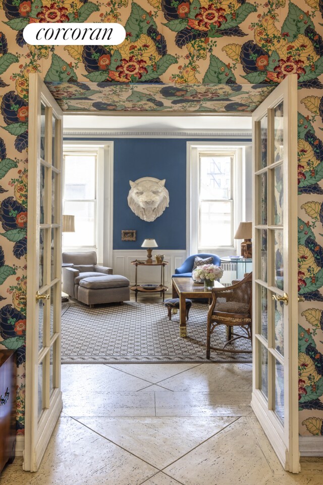 sitting room featuring french doors, a wainscoted wall, and plenty of natural light