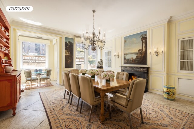 dining room with a decorative wall, a chandelier, ornamental molding, and a premium fireplace