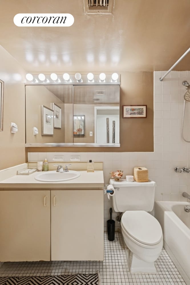 bathroom featuring shower / bath combination, tile patterned flooring, toilet, vanity, and tile walls