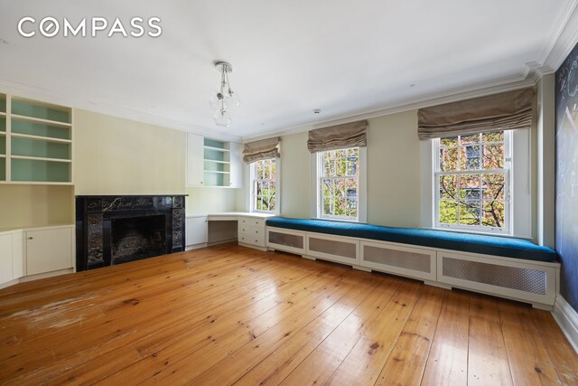 unfurnished living room with crown molding, a high end fireplace, and wood-type flooring