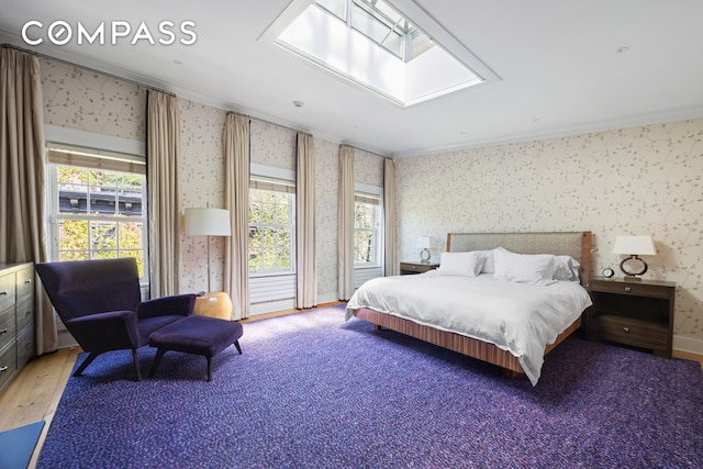 bedroom featuring wallpapered walls, ornamental molding, a skylight, multiple windows, and wood finished floors
