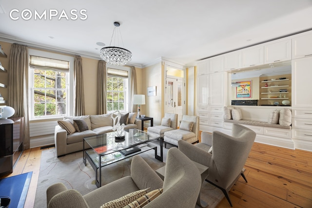 living area featuring ornamental molding, light wood-style flooring, and a chandelier