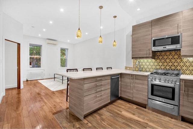 kitchen with stainless steel appliances, a wall unit AC, modern cabinets, a sink, and radiator