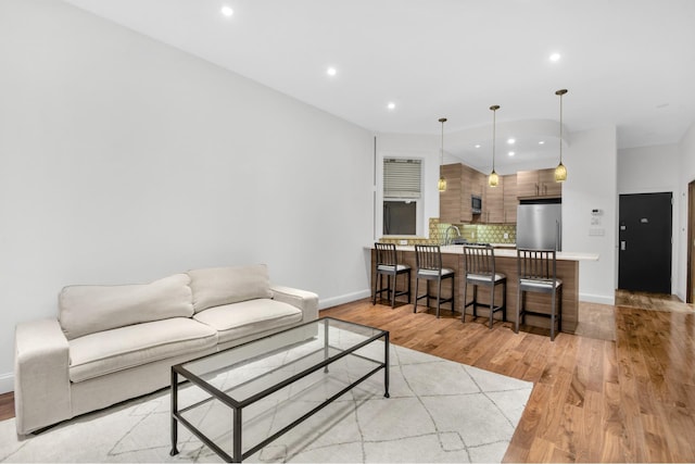living room featuring recessed lighting, baseboards, and light wood-style flooring