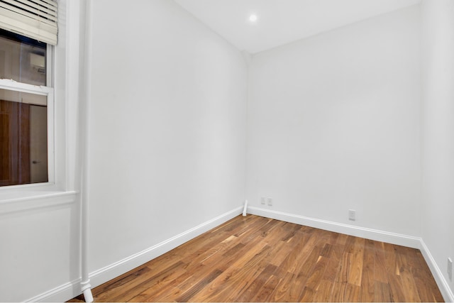empty room featuring wood finished floors, baseboards, and recessed lighting