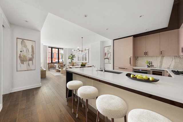 kitchen featuring a sink, light countertops, a chandelier, gas stovetop, and a breakfast bar