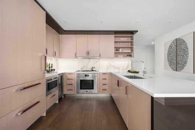 kitchen with appliances with stainless steel finishes, a sink, light brown cabinets, a peninsula, and open shelves