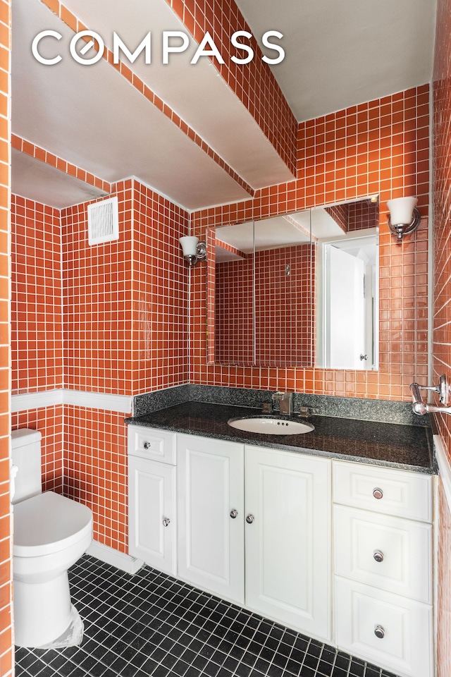 bathroom with tile walls, tile patterned flooring, vanity, and toilet