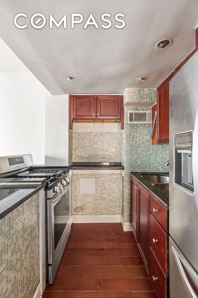 kitchen featuring stainless steel appliances, dark wood finished floors, reddish brown cabinets, baseboards, and a sink
