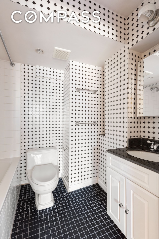 bathroom with tile patterned flooring, tile walls, vanity, and toilet