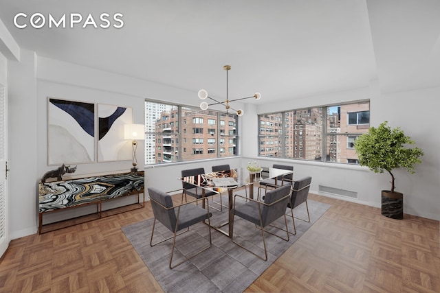 dining area featuring a chandelier, a view of city, and baseboards