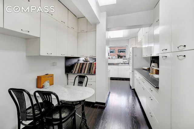 kitchen featuring dark wood finished floors, white cabinetry, and a sink