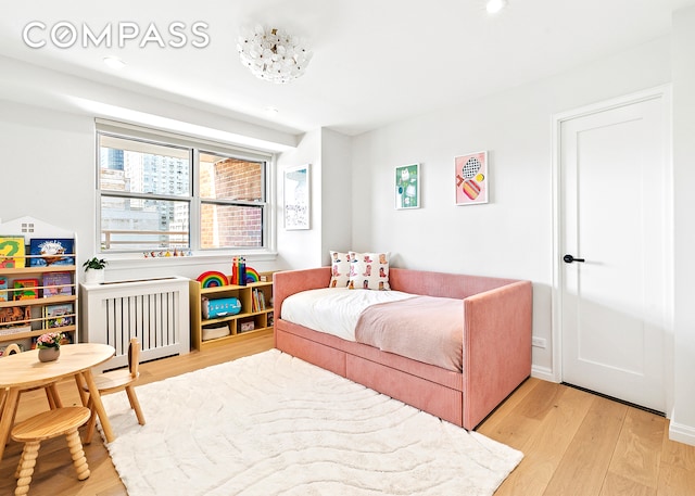 bedroom with radiator heating unit, light wood-style flooring, and recessed lighting