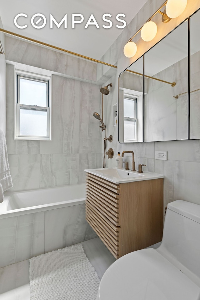 bathroom with toilet, shower / bathtub combination, vanity, and tile walls