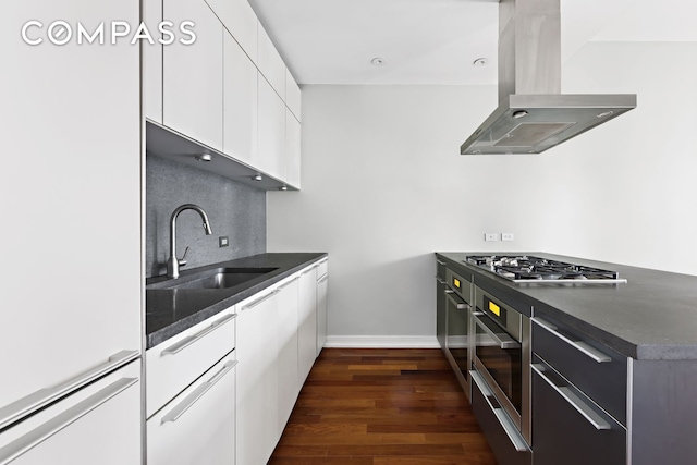 101 Warren St Unit 11L, New York City, NY 10007 - kitchen with island range hood, a sink, appliances with stainless steel finishes, white cabinetry, and dark wood-style floors