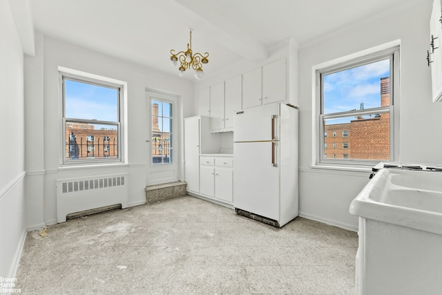 kitchen featuring freestanding refrigerator, radiator, white cabinetry, baseboards, and beamed ceiling
