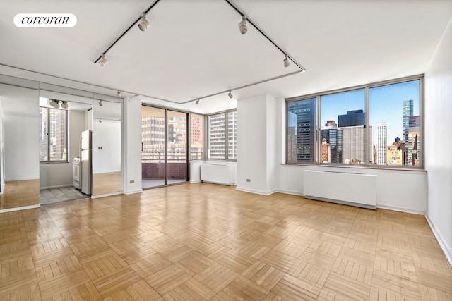 unfurnished room featuring track lighting and baseboards