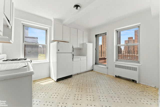 kitchen with white appliances, radiator, white cabinets, beamed ceiling, and light flooring