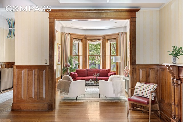 623 2nd St, New York City, NY 11215 - living area featuring wallpapered walls, radiator heating unit, a wainscoted wall, wood finished floors, and ornamental molding
