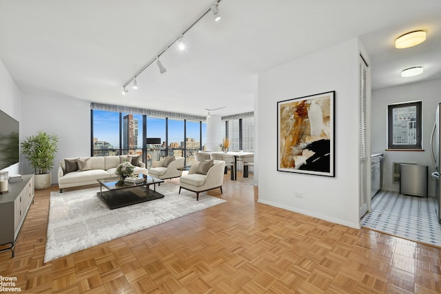 living area featuring baseboards, track lighting, and a city view