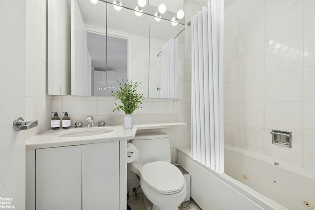 bathroom with tile walls, toilet, backsplash, a combined bath / shower with jetted tub, and vanity