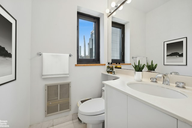 bathroom featuring heating unit, toilet, vanity, and tile patterned flooring