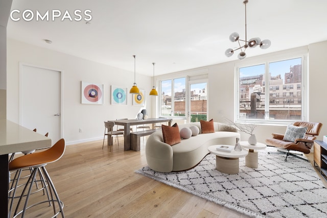 living room featuring light wood finished floors, healthy amount of natural light, baseboards, and a chandelier