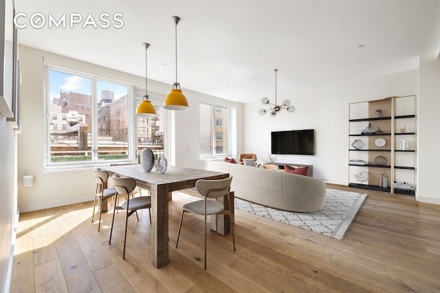 dining room featuring wood-type flooring, a chandelier, and baseboards