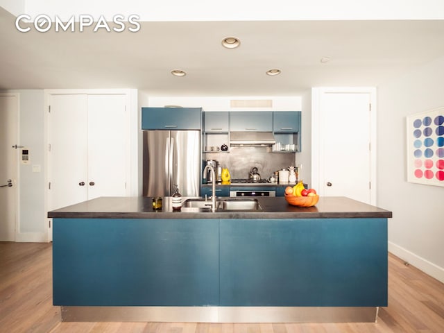 84 Front St Unit 5E, New York City, NY 11201 - kitchen with appliances with stainless steel finishes, dark countertops, a sink, light wood finished floors, and baseboards
