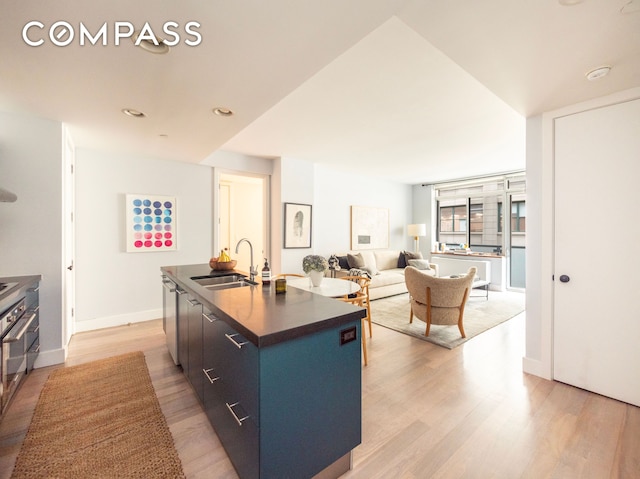 84 Front St Unit 5E, New York City, NY 11201 - kitchen with a sink, dark countertops, dishwasher, a center island with sink, and light wood-style flooring