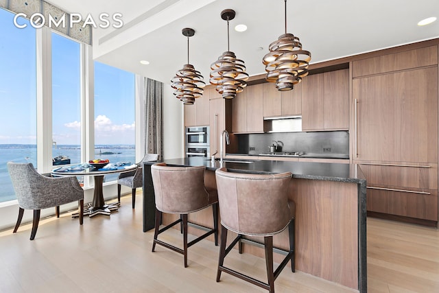 kitchen with modern cabinets, dark countertops, a breakfast bar, gas cooktop, and recessed lighting