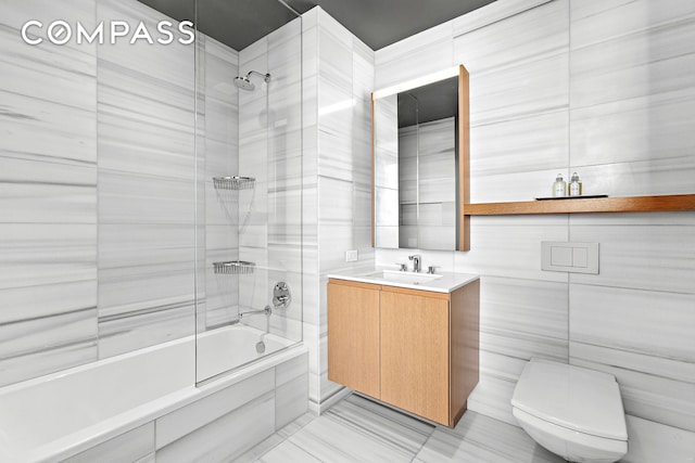 full bathroom featuring tiled shower / bath combo, vanity, toilet, tile walls, and tile patterned floors