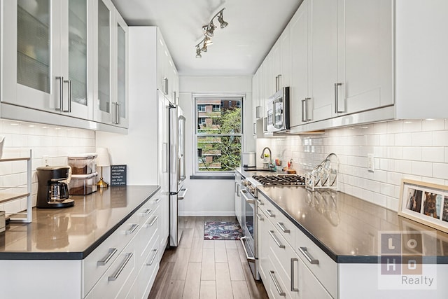 455 Fdr Dr Unit B405, New York City, NY 10002 - kitchen featuring stainless steel appliances, dark countertops, tasteful backsplash, and white cabinetry