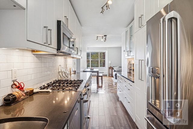 455 Fdr Dr Unit B405, New York City, NY 10002 - kitchen featuring stainless steel appliances, dark countertops, dark wood-style flooring, tasteful backsplash, and white cabinets