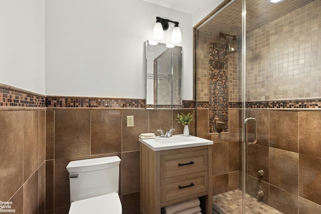 bathroom featuring a stall shower, tile walls, vanity, and toilet