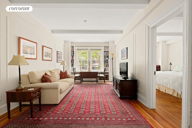 living area featuring beamed ceiling and baseboards