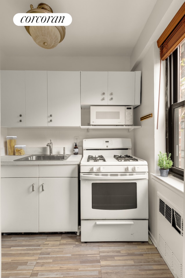 405 E 63rd St Unit 5N, New York City, NY 10065 - kitchen with white appliances, a sink, radiator, and white cabinetry