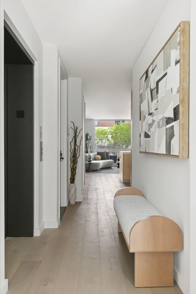corridor with light wood-style floors and baseboards