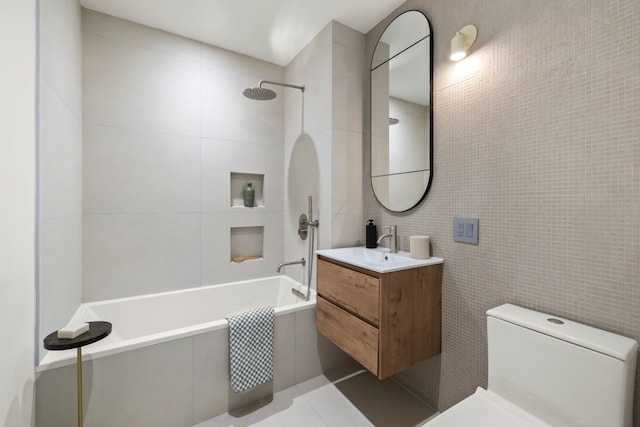 full bath featuring tile walls, toilet, tiled shower / bath combo, and vanity