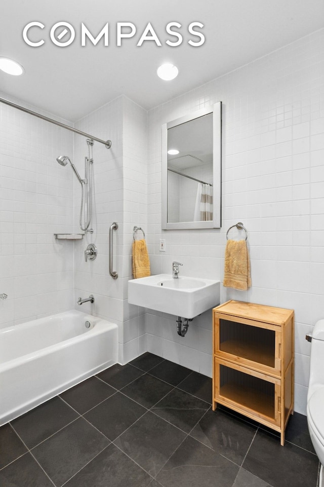 bathroom featuring tile patterned floors, tile walls, a sink, toilet, and shower / bath combo with shower curtain