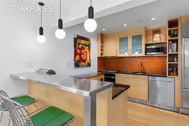 kitchen with stainless steel counters, appliances with stainless steel finishes, open shelves, light wood finished floors, and tasteful backsplash