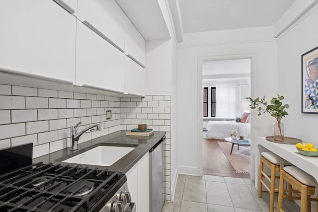 205 E 78th St Unit 5S, New York City, NY 10075 - kitchen with appliances with stainless steel finishes, dark countertops, a sink, white cabinetry, and tasteful backsplash