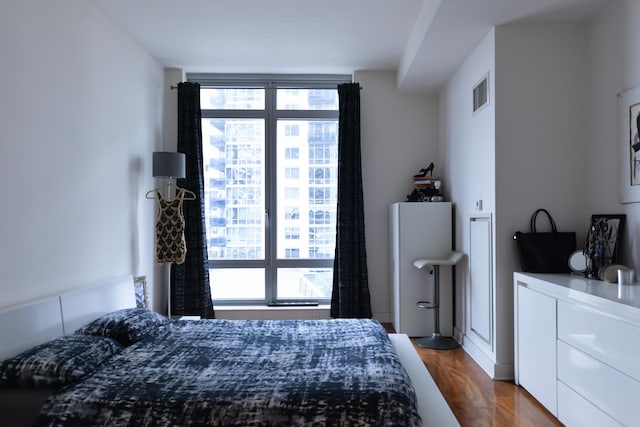 bedroom with multiple windows and dark wood-style flooring
