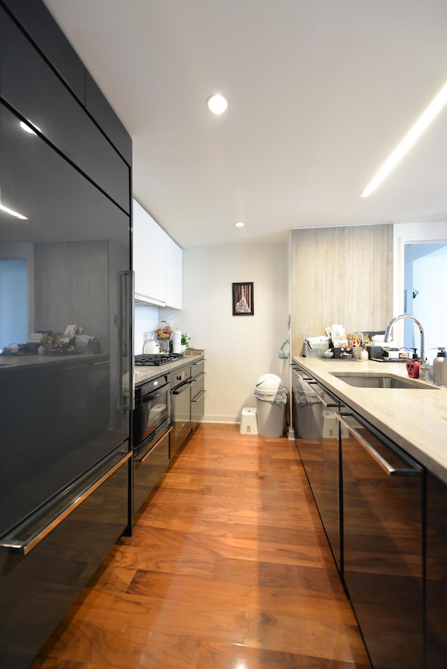 kitchen with modern cabinets, a sink, appliances with stainless steel finishes, light countertops, and white cabinetry