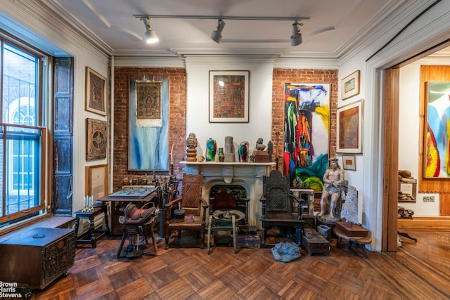 sitting room featuring brick wall, plenty of natural light, rail lighting, and ornamental molding