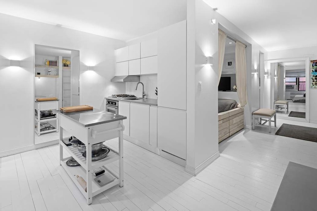 kitchen featuring modern cabinets, white cabinetry, a sink, stainless steel oven, and light countertops