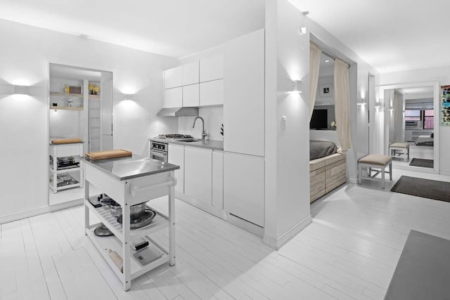 kitchen featuring modern cabinets, white cabinetry, a sink, stainless steel oven, and light countertops