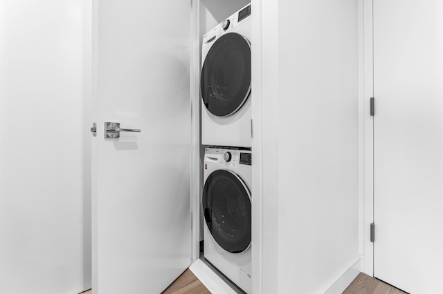 clothes washing area featuring stacked washer and clothes dryer and light wood-style flooring