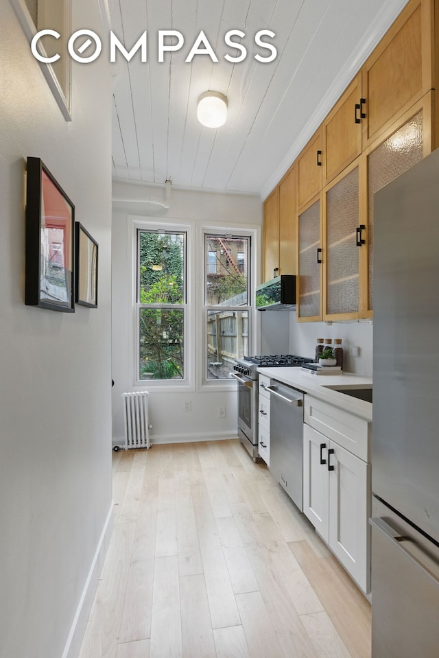152 N 9th St Unit 1R, New York City, NY 11249 - kitchen with appliances with stainless steel finishes, radiator, glass insert cabinets, light wood-type flooring, and wood ceiling